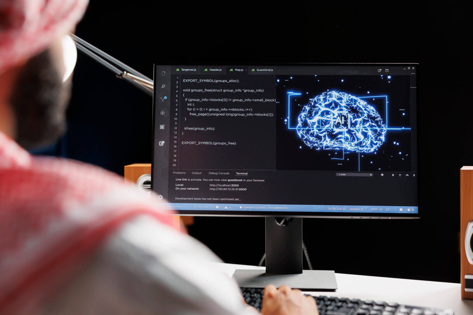 Persona trabajando en un ordenador con código en pantalla, mientras visualiza un gráfico de cerebro digital que representa el procesamiento de datos en IA generativa.