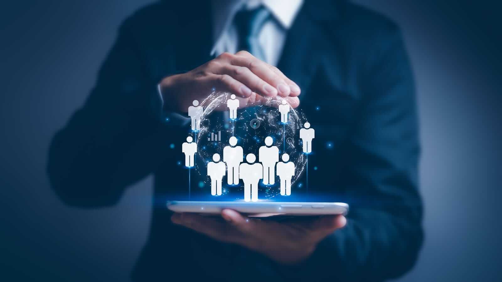 Ejecutivo sostiene una tablet de la que emergen íconos de usuarios conectados en red global, simbolizando cómo LSM mejora la escalabilidad y la gestión de datos en bases de datos NoSQL.