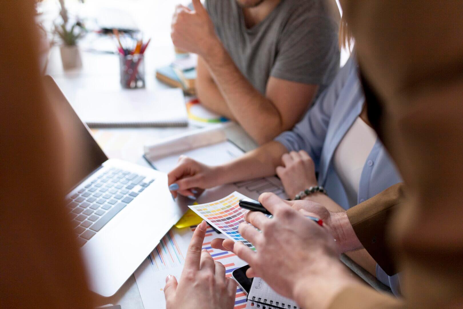 Grupo de profesionales reunido frente a un ordenador analizando gráficos y paletas de color durante una planificación de proyectos de convergencia TI/OT.