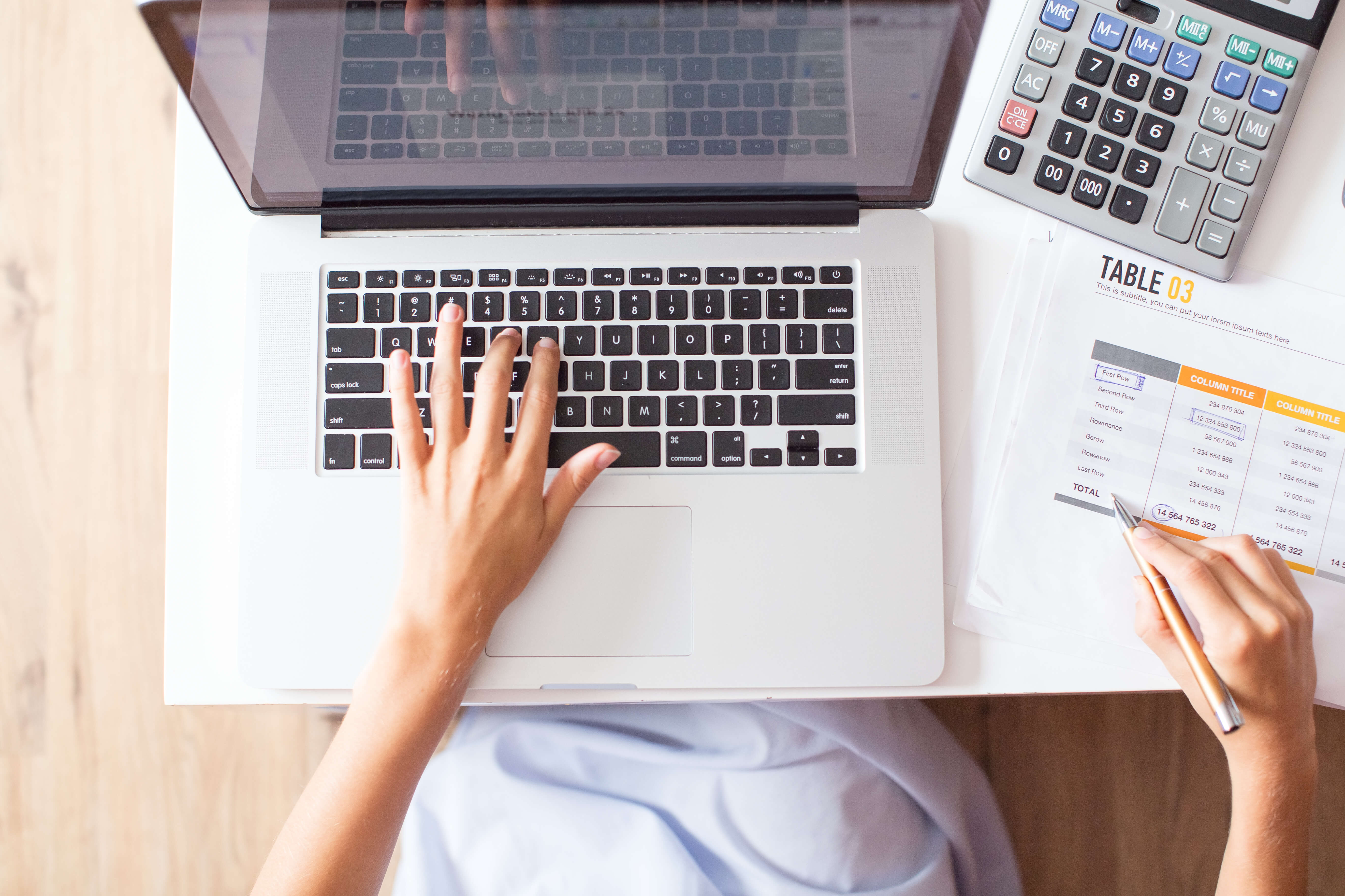 Manos sobre un portátil con hojas de cálculo y calculadora, representando la gestión del presupuesto IT en una empresa.