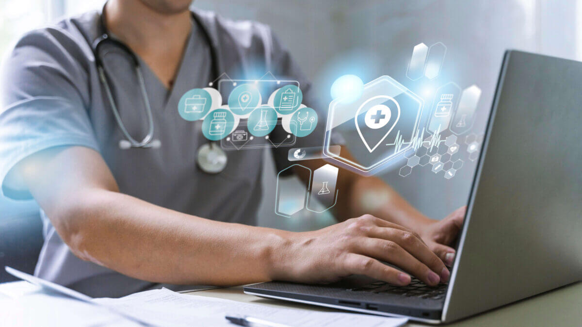 Profesional de la salud frente a una laptop con iconos digitales de protección de datos que ilustran ciberseguridad en salud.