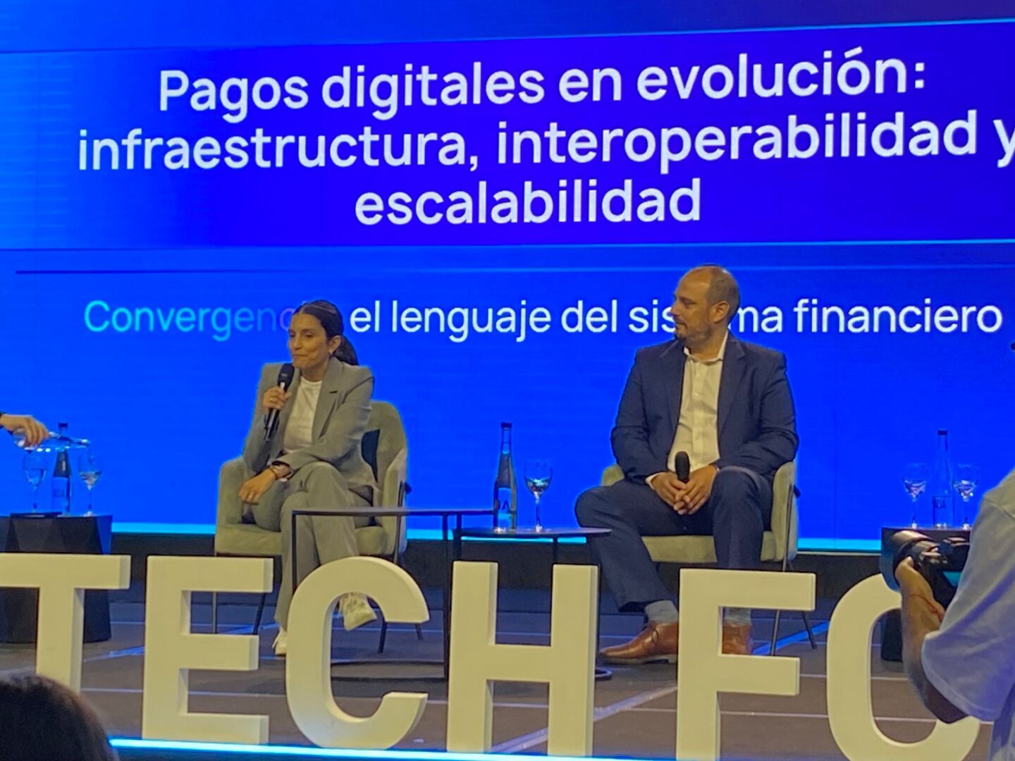 Panel en el Argentina Fintech Forum con dos oradores en un escenario azul mientras se debate sobre pagos digitales, infraestructura, interoperabilidad y escalabilidad; la escena corresponde al panel donde participaron Candelaria Villagra y Daniel Conte según la información provista por la organización.