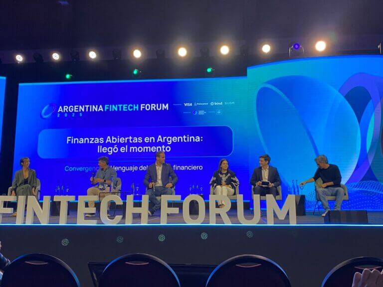 Panel de expertos en el Argentina Fintech Forum 2025 que analiza el avance del Open Finance en Argentina, con seis referentes del ecosistema sentados en el escenario frente a una pantalla institucional.