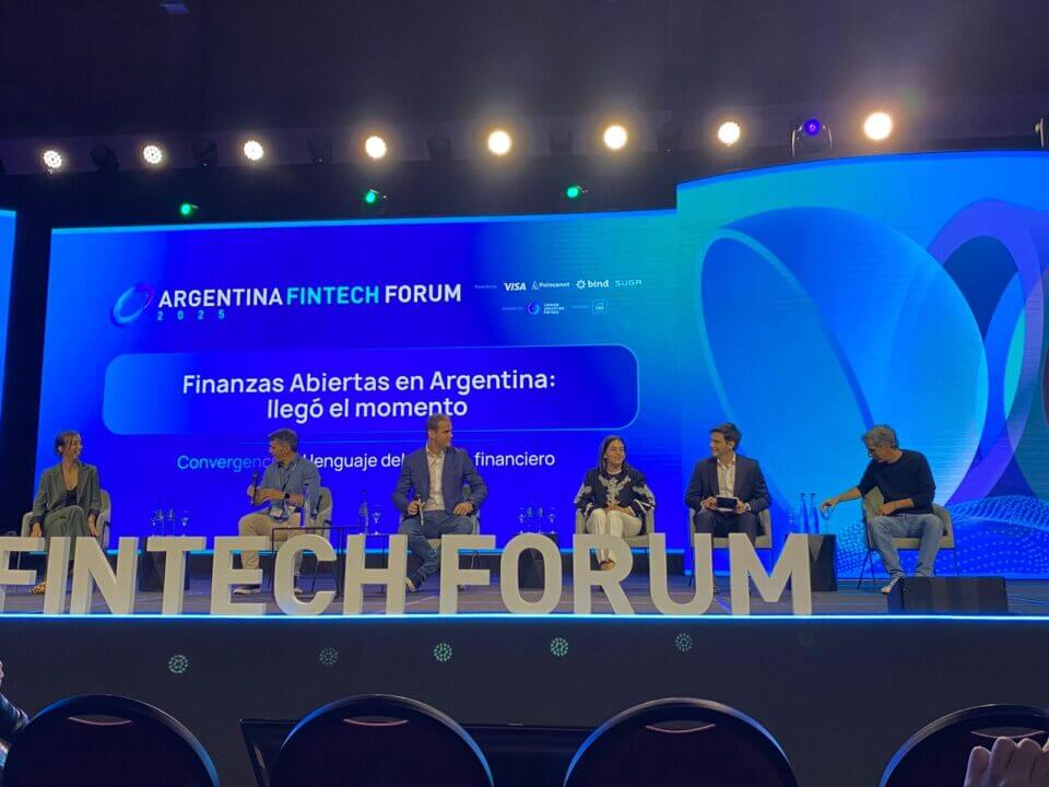 Panel de expertos en el Argentina Fintech Forum 2025 que analiza el avance del Open Finance en Argentina, con seis referentes del ecosistema sentados en el escenario frente a una pantalla institucional.