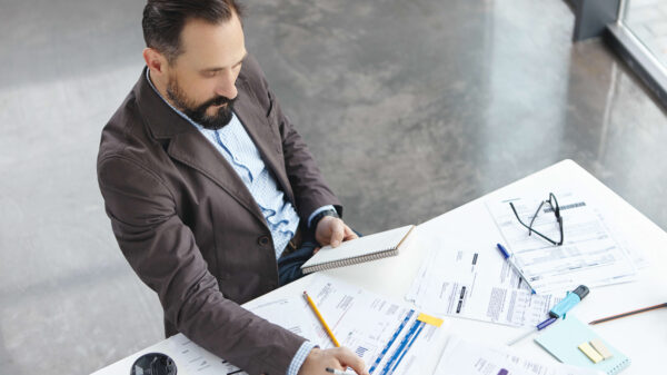 Profesional en oficina analiza reportes y métricas sobre una mesa, como parte de la planificación de un BCP para continuidad del negocio en la nube.