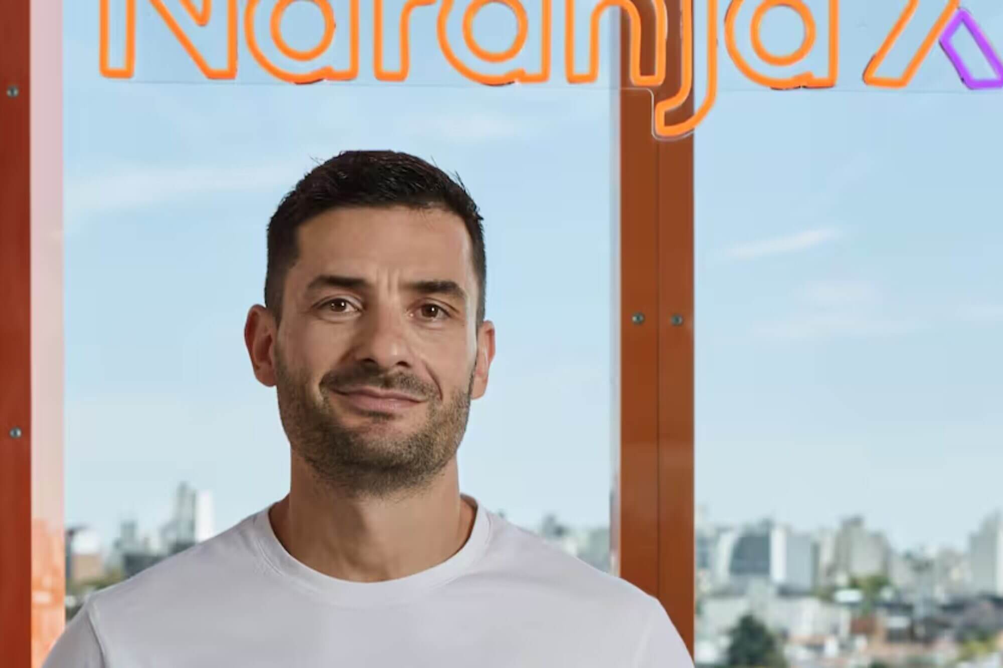 Gonzalo Ozán, CIO y CTO de Naranja X, retrato corporativo frente al logo de la fintech en sus oficinas.