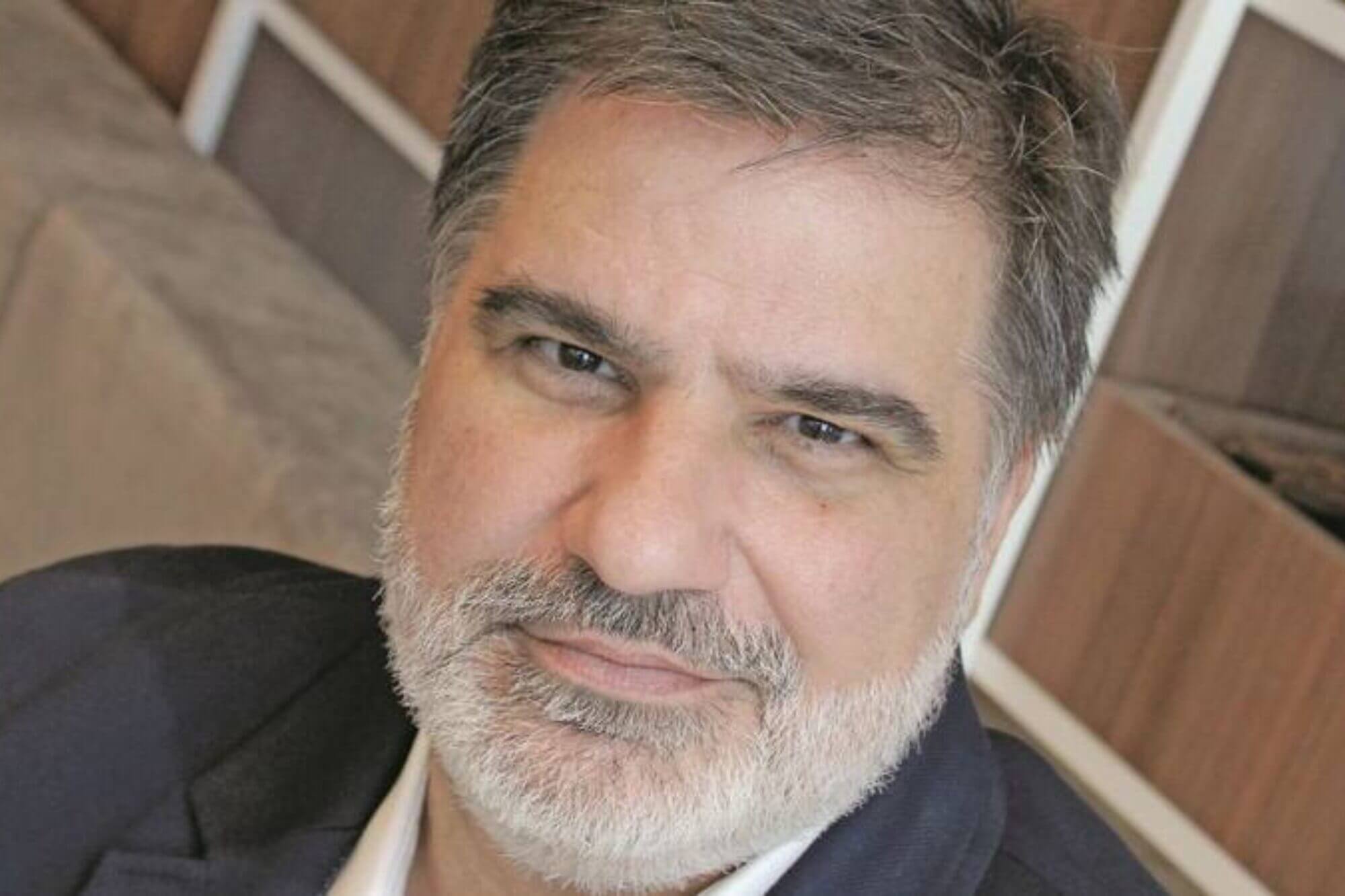 Primer plano de un ejecutivo con saco oscuro y barba canosa, en una foto de perfil para un artículo sobre Eduardo Martínez.