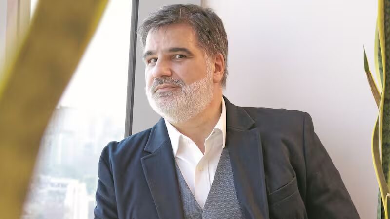 Ejecutivo con saco azul y camisa blanca, de pie junto a una ventana, en una imagen para un artículo sobre Eduardo Martínez.