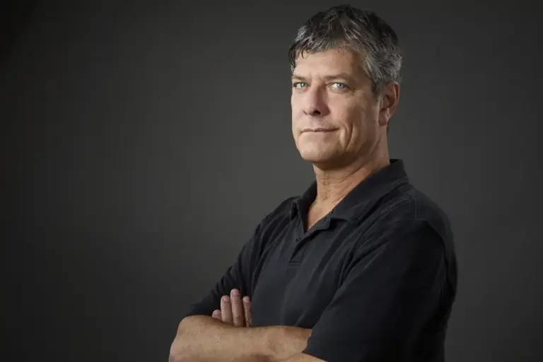 Pergolini posa con los brazos cruzados en un retrato de estudio con fondo oscuro durante una entrevista sobre inteligencia artificial.