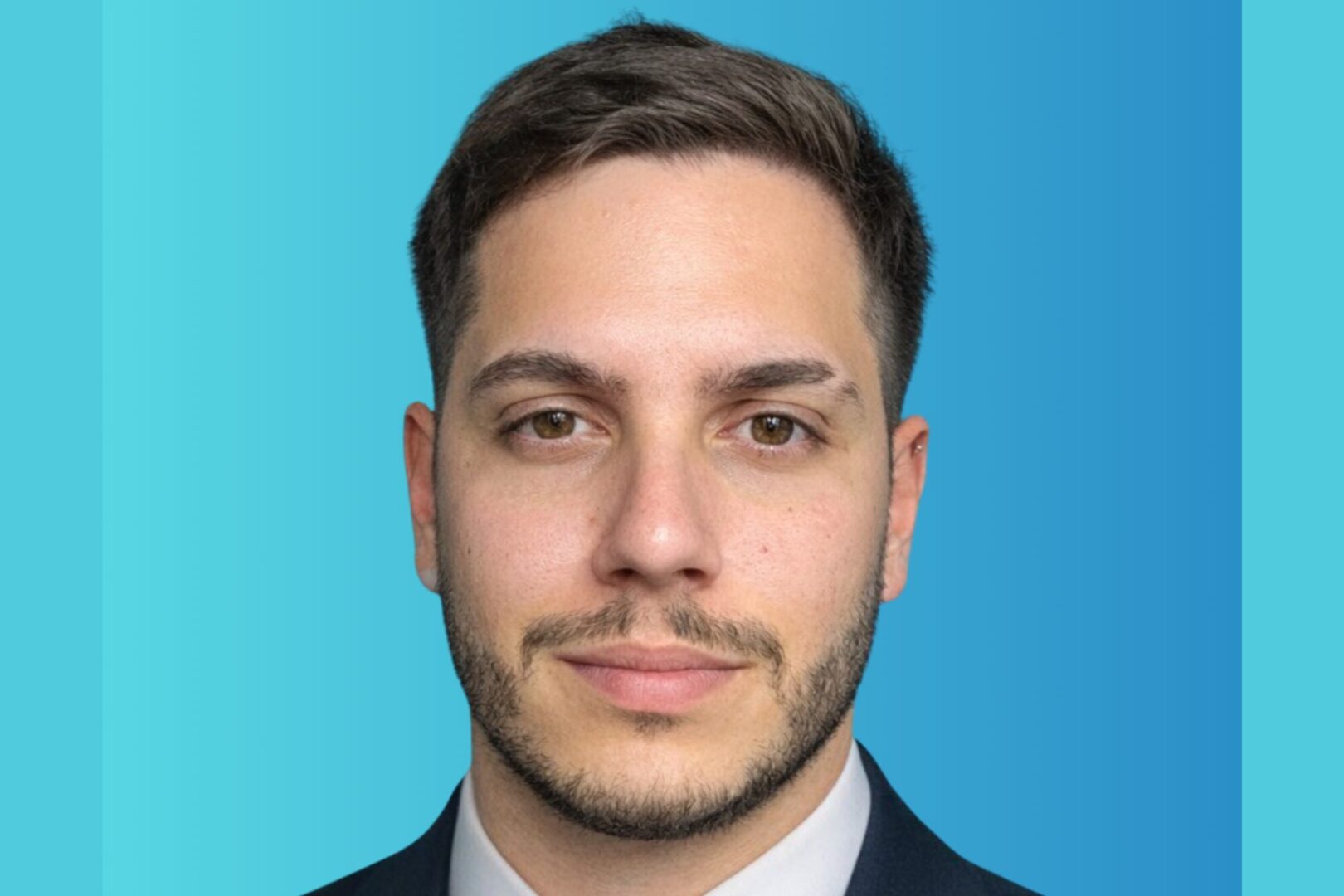 Retrato de ejecutivo con traje sobre fondo azul para nota de ciberseguridad en consumo masivo.