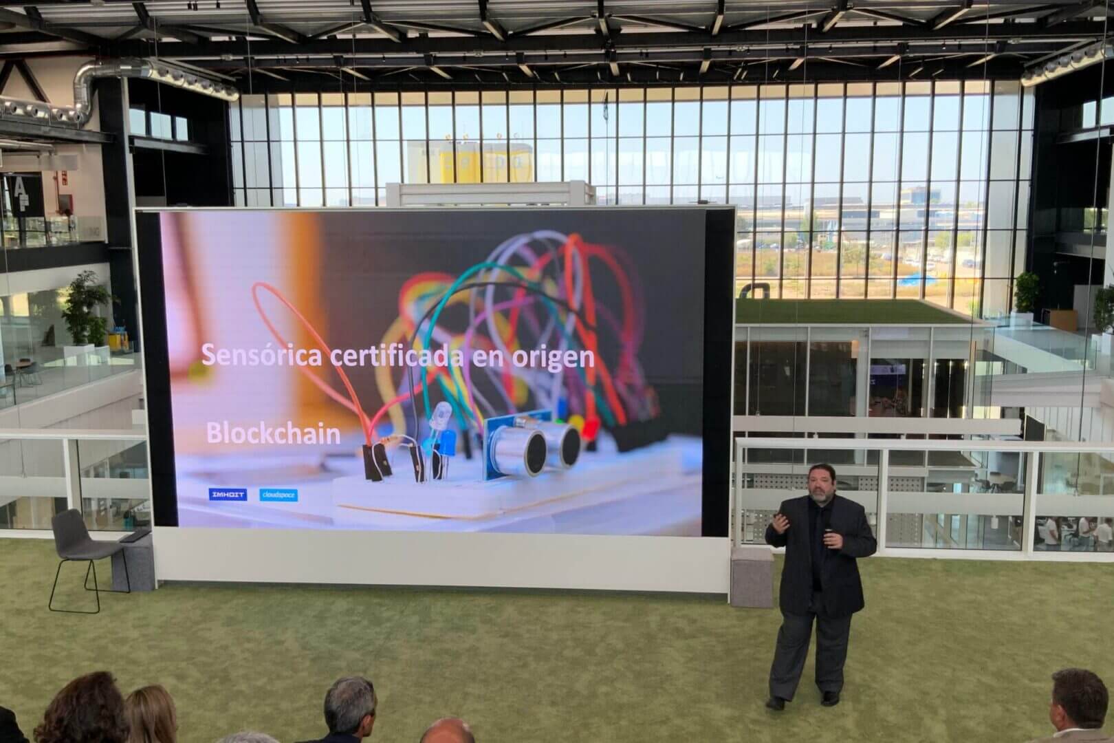 Expositor en un auditorio durante una presentación sobre blockchain, sensórica y ciberseguridad en consumo masivo.