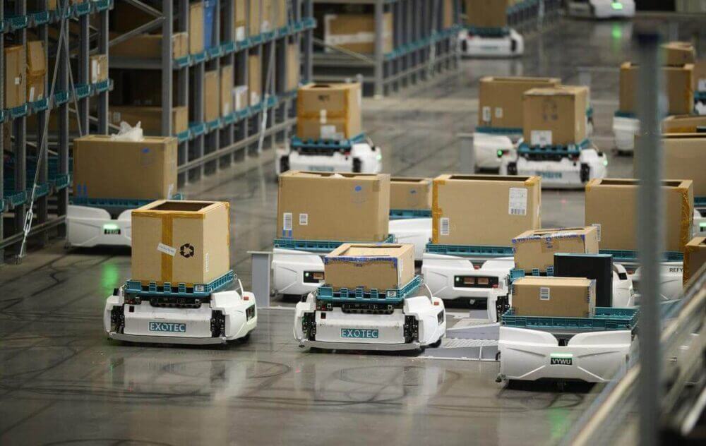 Robots Skypod de Exotec transportan cajas en un almacén automatizado, como parte de una solución de robótica logística para picking.