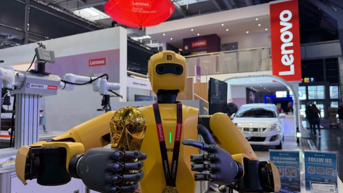 Robot humanoide amarillo en el stand de Lenovo durante una feria industrial, en una imagen sobre IA aplicada a manufactura y automatización.