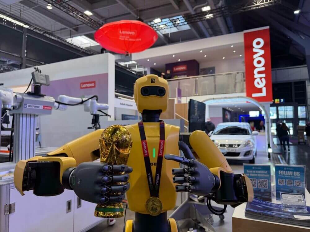 Robot humanoide amarillo en el stand de Lenovo durante una feria industrial, en una imagen sobre IA aplicada a manufactura y automatización.