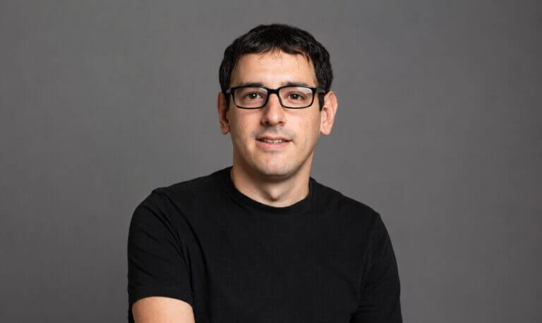 Retrato horizontal de Fernando Scorpiniti, CTO de etermax, con anteojos y remera negra sobre fondo gris.