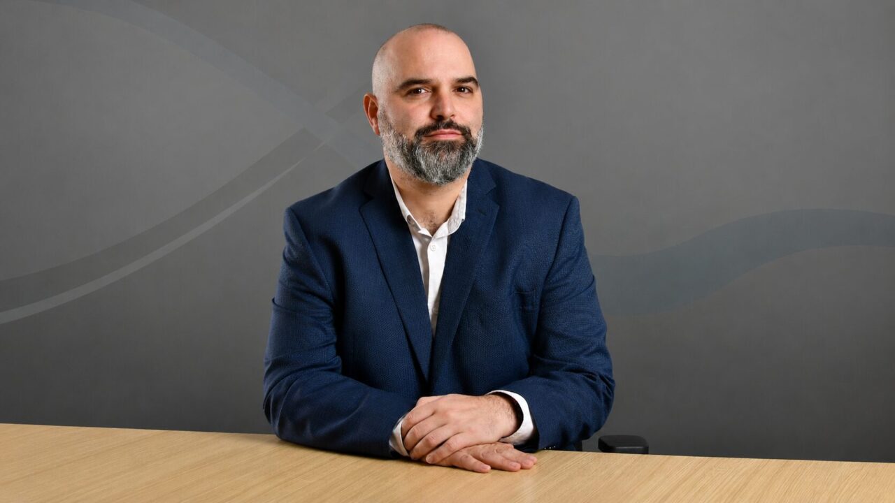 Germán Garay, CTIO de Metrotel, sentado en una mesa con saco azul frente a un fondo gris corporativo.