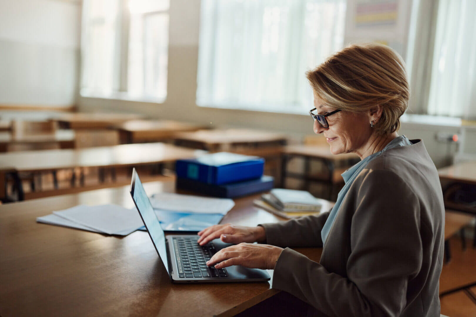 Docente trabaja con una laptop en un aula vacía, relacionada con el uso de learning analytics para tomar decisiones educativas.