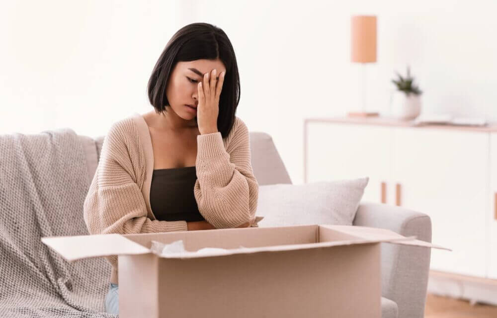 Cliente preocupada revisa una caja abierta, ilustrando cómo la calidad predictiva puede ayudar a evitar reclamos por fallas de producto.
