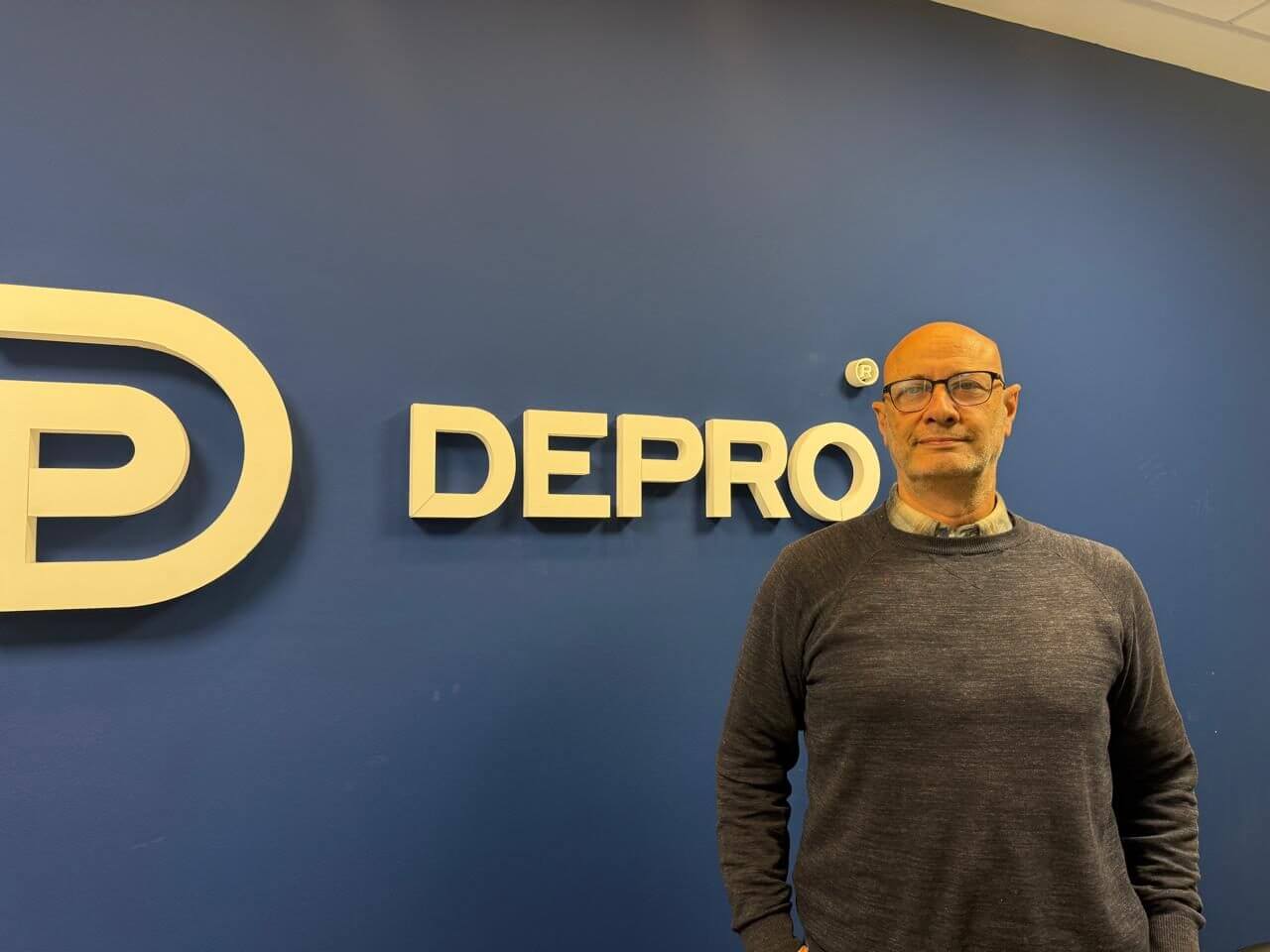 Gustavo Radyk, socio gerente de Depro Ingeniería y Arquitectura, frente al logo de la empresa, consultado sobre infraestructura y gemelos digitales en alimentos y bebidas.