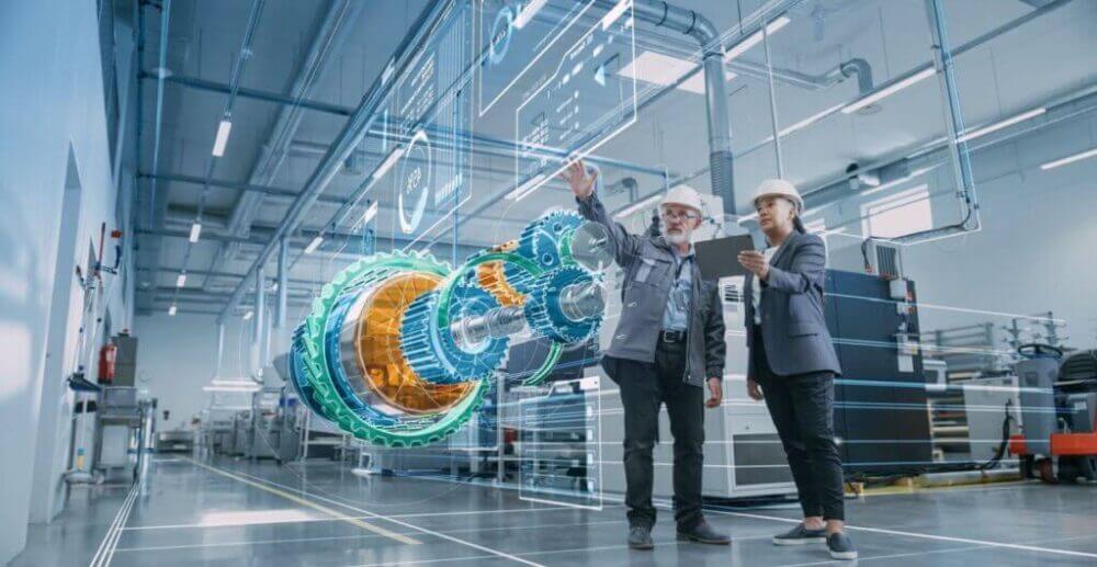 Dos profesionales con casco analizan una simulación industrial con un gemelo digital de maquinaria dentro de una planta conectada.