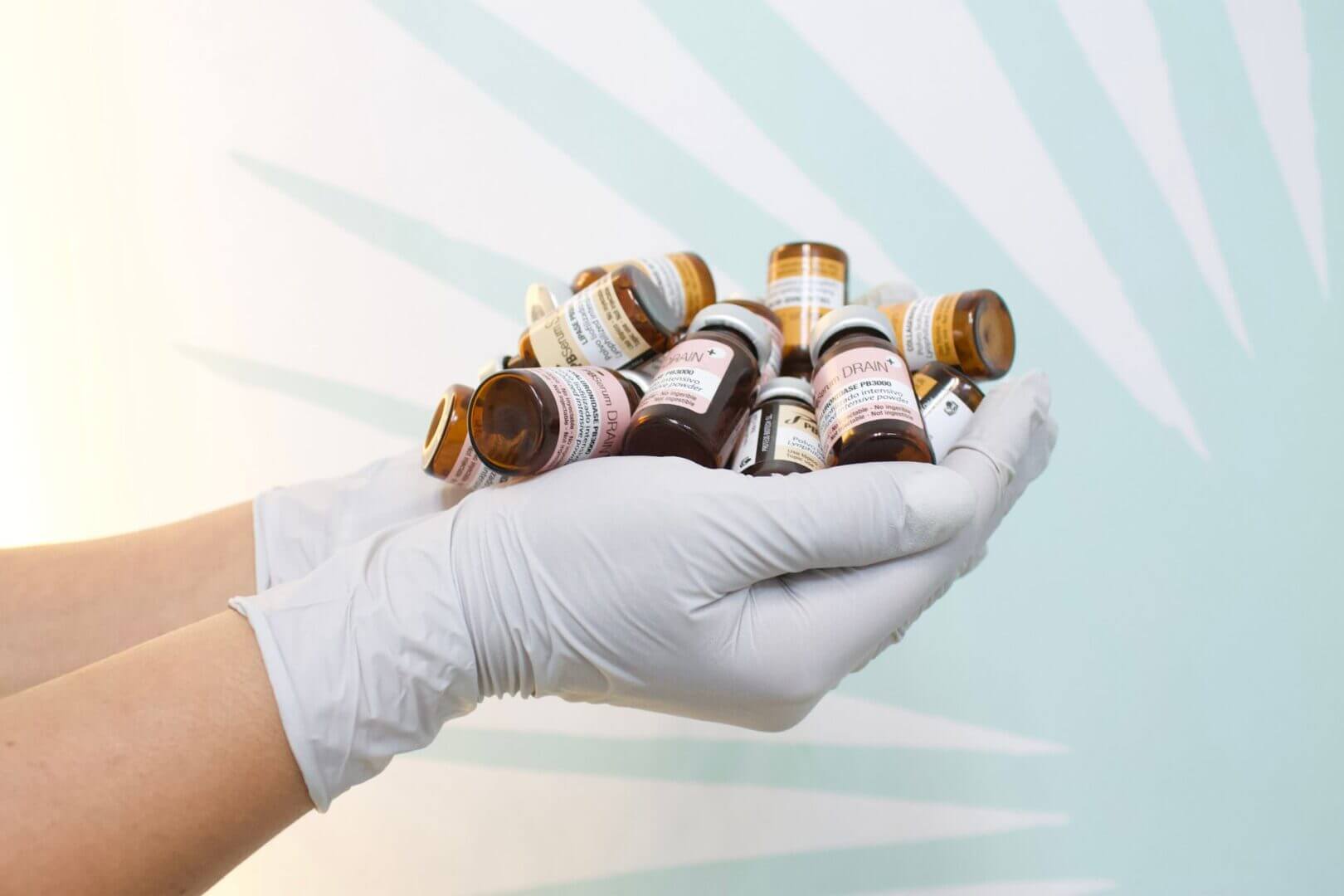 Manos con guantes sostienen frascos de medicamentos, en una imagen vinculada a farmacias, salud y procesamiento digital de pagos.