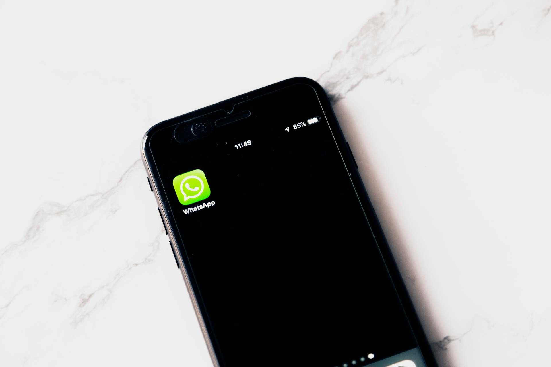 Teléfono móvil con el ícono de WhatsApp en pantalla, asociado a fraudes por mensajería e ingeniería social.