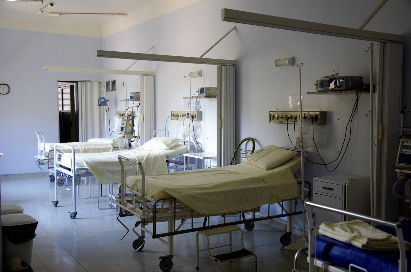 Camas hospitalarias vacías en un pasillo iluminado, en un entorno clínico preparado para la atención de pacientes.