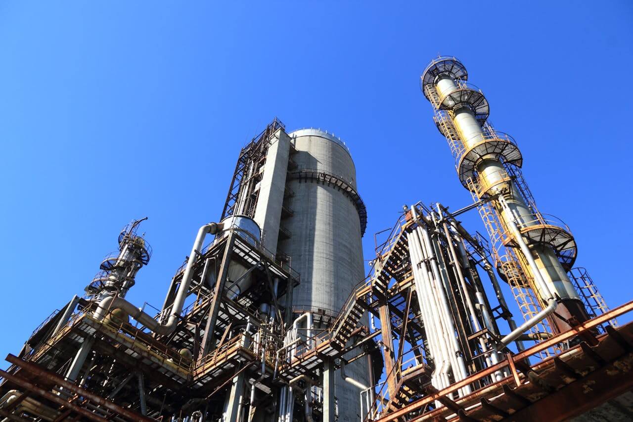 Torres, tanques y estructuras metálicas de una planta industrial bajo cielo despejado.