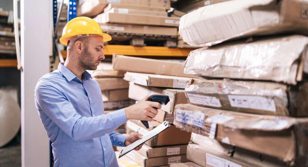 Operario escanea paquetes en un almacén, proceso que puede complementarse con RFID en logística para mejorar la trazabilidad.