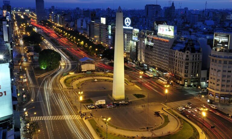 Vista nocturna del Obelisco y la avenida 9 de Julio con luces de vehículos, vinculada a la movilidad urbana en Buenos Aires.
