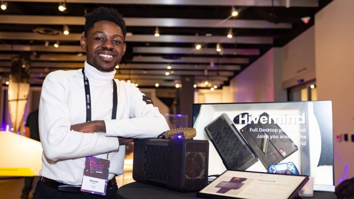 Emprendedor junto a una eGPU y una pantalla de Project Hivemind en un evento tecnológico.
