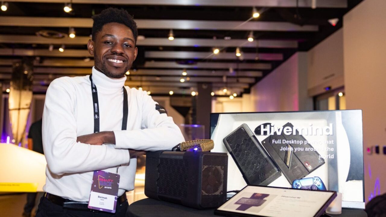 Emprendedor junto a una eGPU y una pantalla de Project Hivemind en un evento tecnológico.