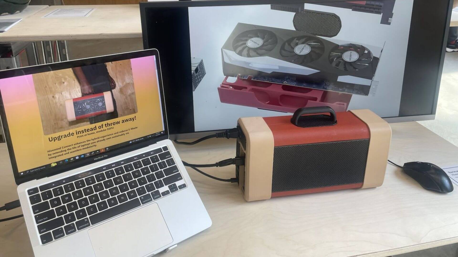 Dispositivo eGPU conectado a una notebook y a un monitor externo con una tarjeta gráfica en pantalla.