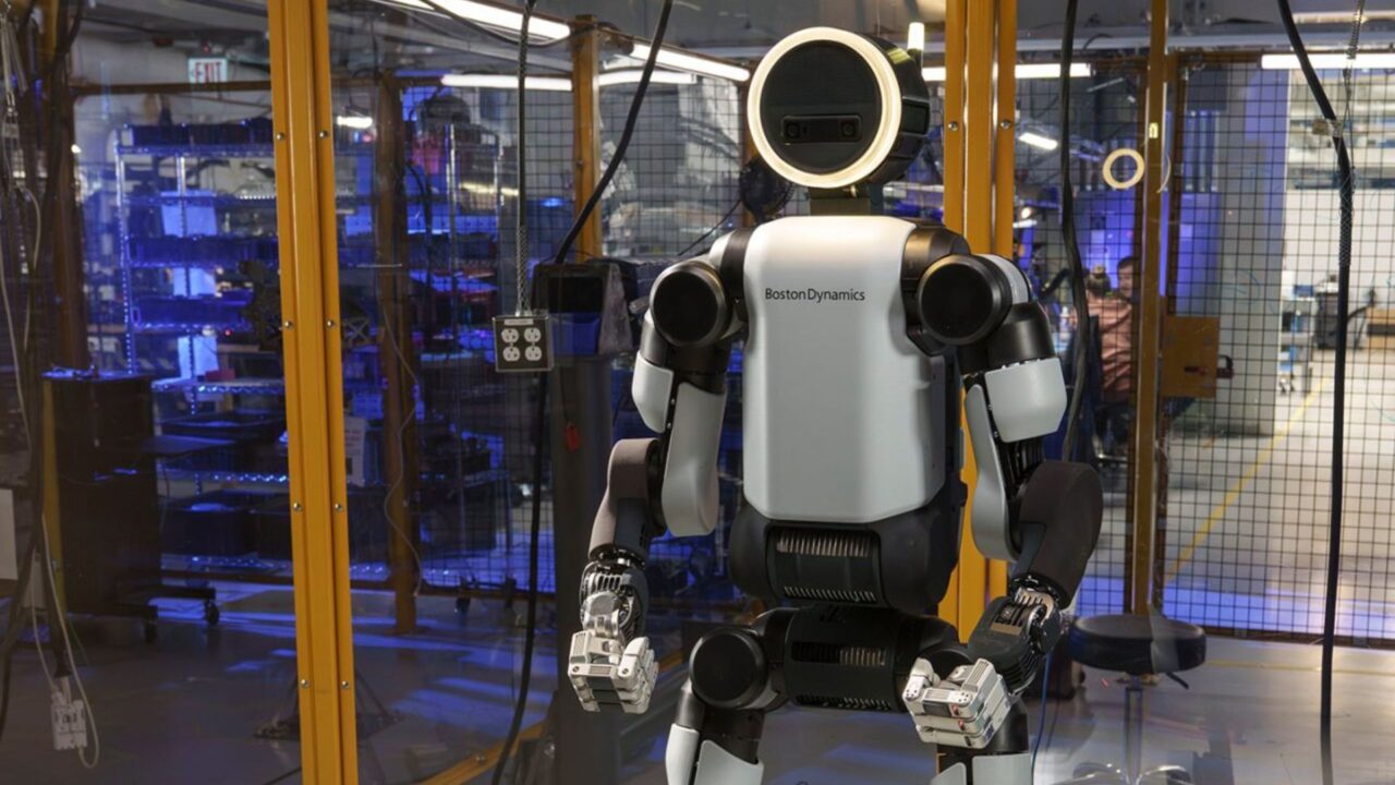 Robot humanoide de Boston Dynamics en un laboratorio de pruebas, con estructura blanca y negra detrás de una barrera de seguridad.