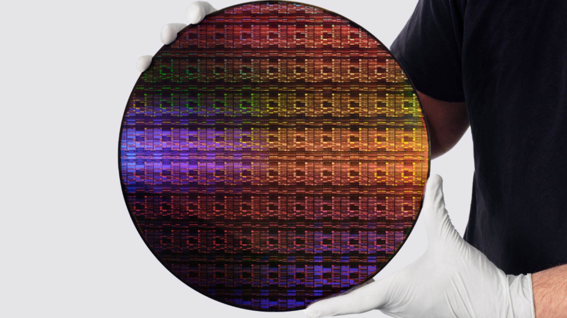 Persona con guantes sostiene una oblea de silicio usada en la fabricación de chips de IA y semiconductores avanzados.