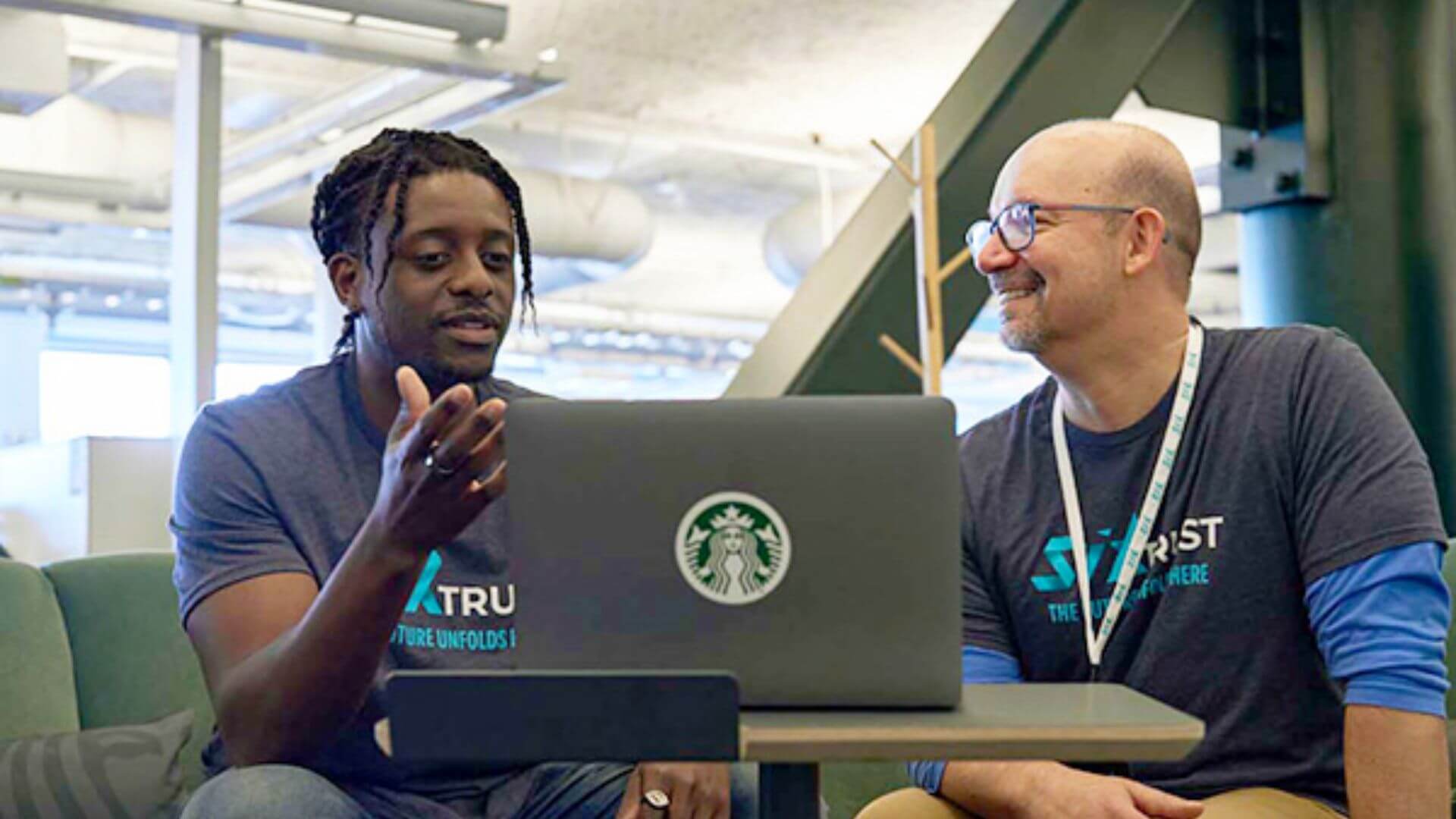 Dos integrantes del equipo tecnológico de Starbucks trabajan frente a una computadora portátil en las oficinas de la compañía.