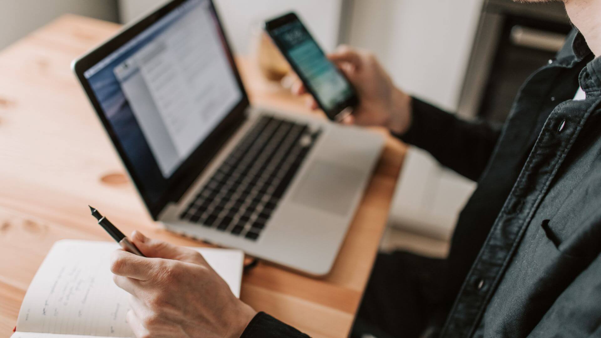 Persona utiliza una notebook, un celular y un cuaderno para gestionar pedidos comerciales mediante Galo AI.