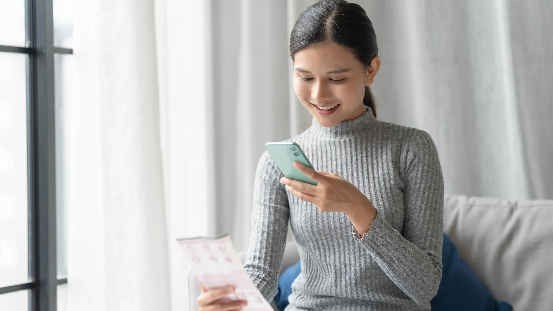 Mujer consulta su celular en una imagen que representa los servicios digitales que Conexa integra para bancos, billeteras virtuales y eCommerce.