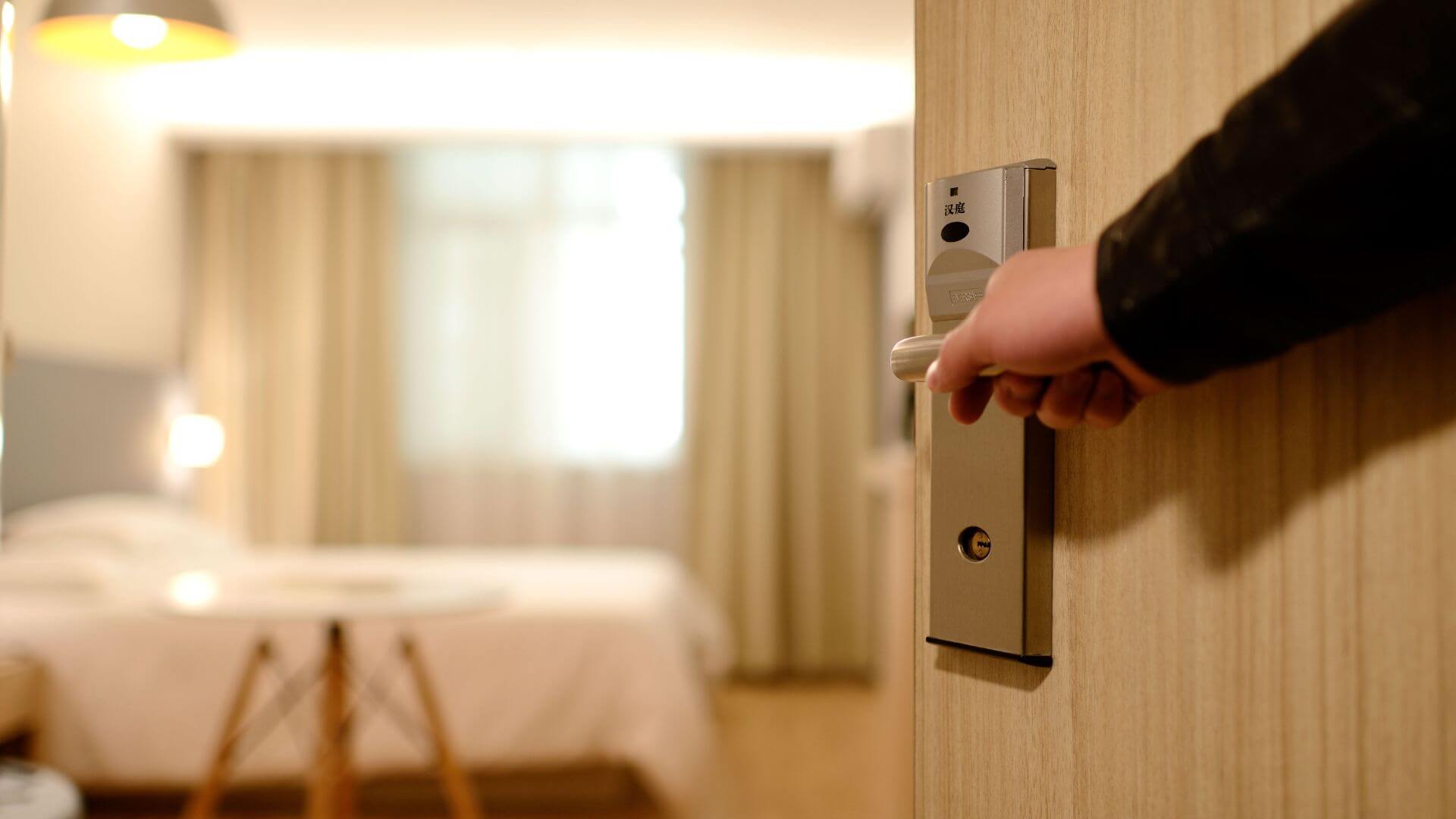 Persona que abre la puerta de una habitación de hotel con una cerradura electrónica.