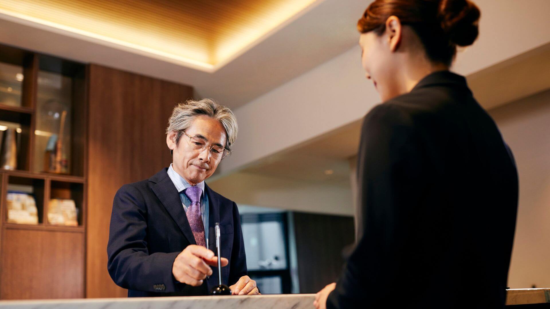 Huésped en la recepción de un hotel durante el proceso de check-in con una empleada del establecimiento.