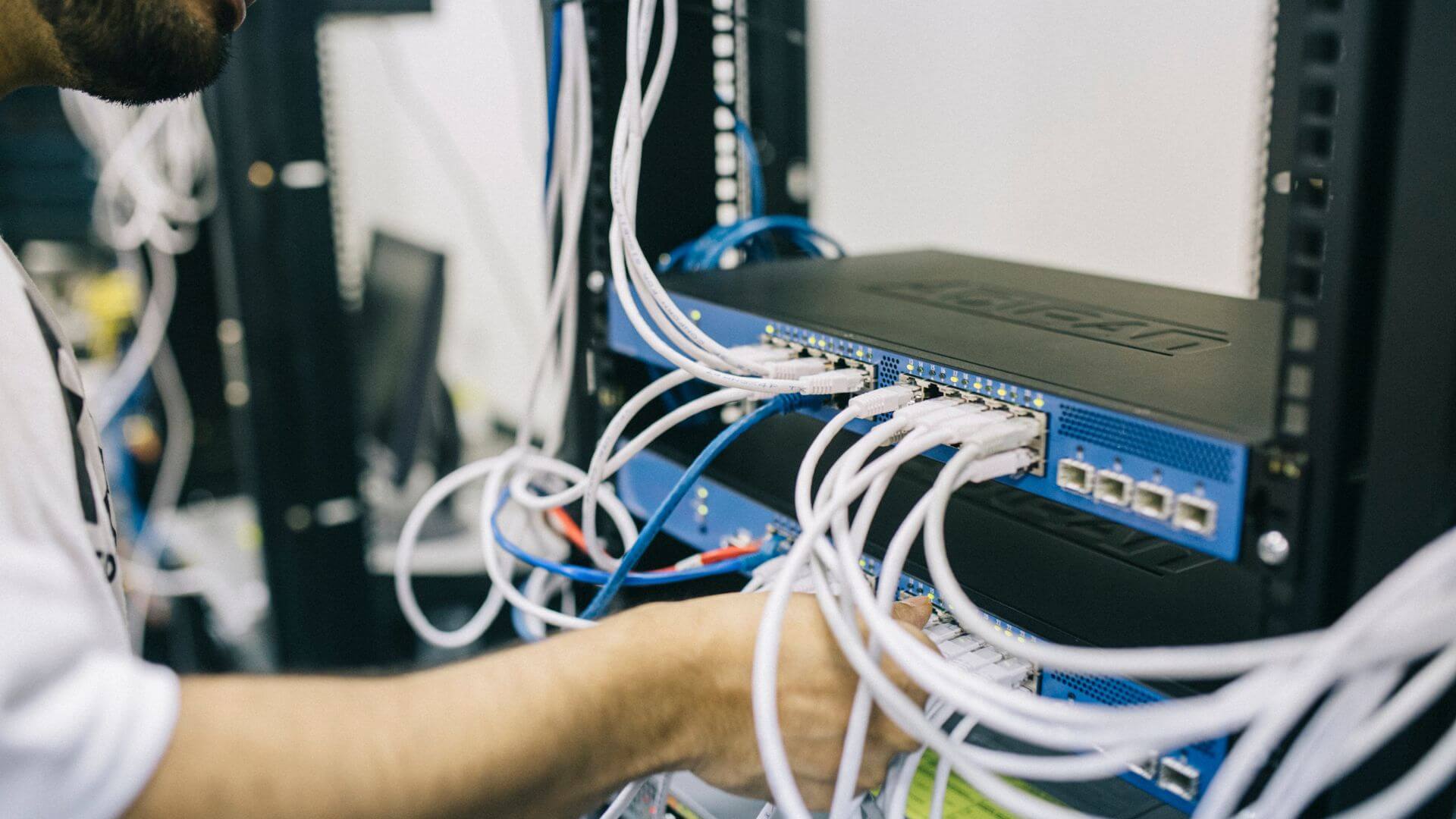 Técnico configura conmutadores y cableado Ethernet para la infraestructura de Wi-Fi 7 en hoteles.
