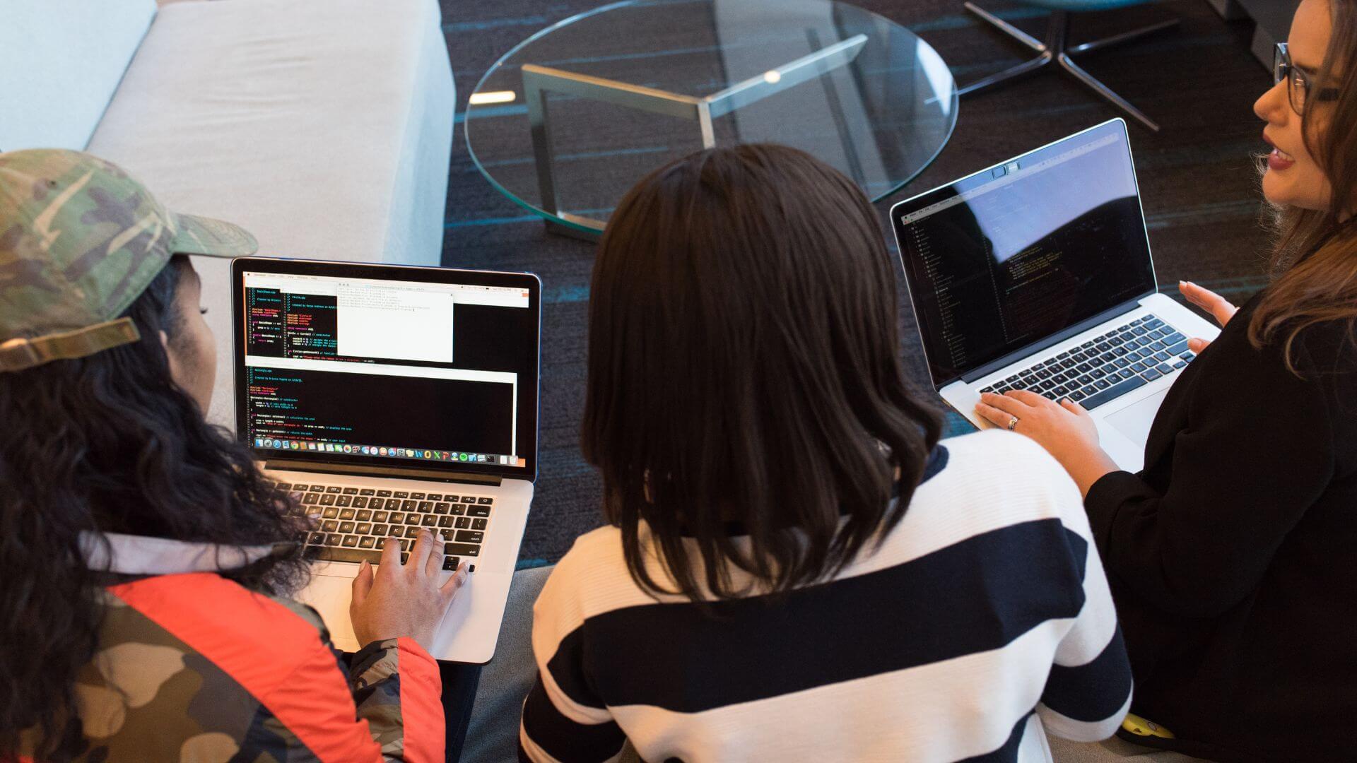 Equipo de desarrollo trabaja con computadoras portátiles en un proyecto tecnológico vinculado con la visión de Sam Altman sobre startups e inteligencia artificial.