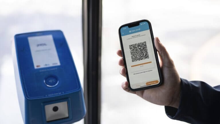 Pasajero utiliza un código QR en tranporte público para pagar el boleto con el celular frente a una validadora.