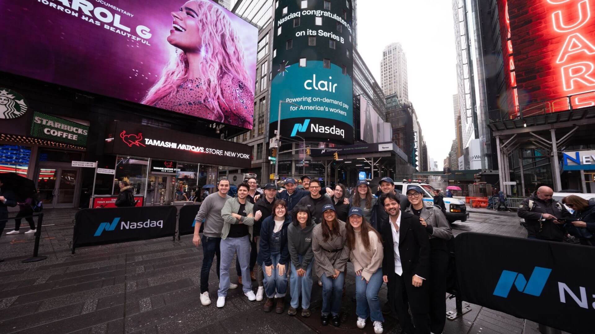Equipo de Clair reunido frente a la pantalla de Nasdaq en Times Square, Nueva York.
