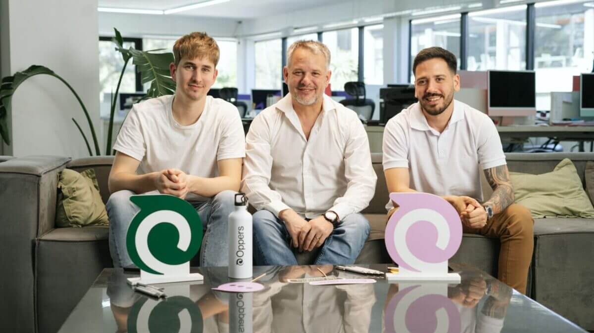 Tres fundadores de Oppers sentados en una oficina junto a elementos con el logo de la empresa.