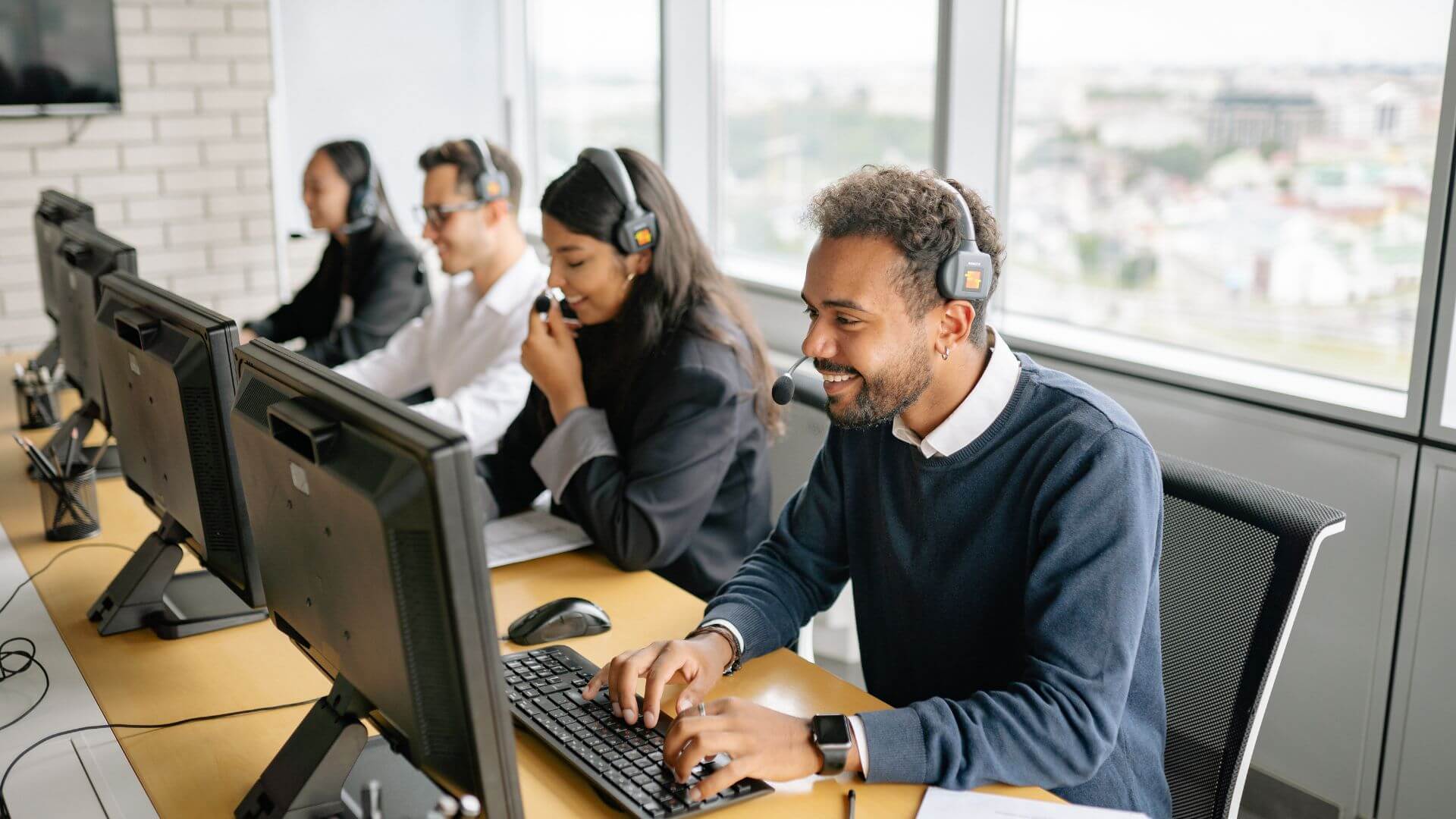 Equipo de operadores con auriculares trabaja frente a computadoras en un call center vinculado a Oppers.