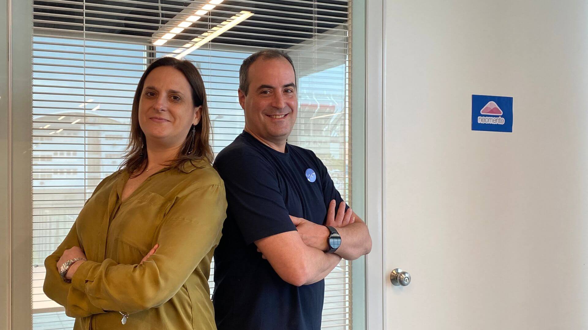 Dos fundadores de Neomente posan en una oficina junto al logo de la startup argentina de salud mental.