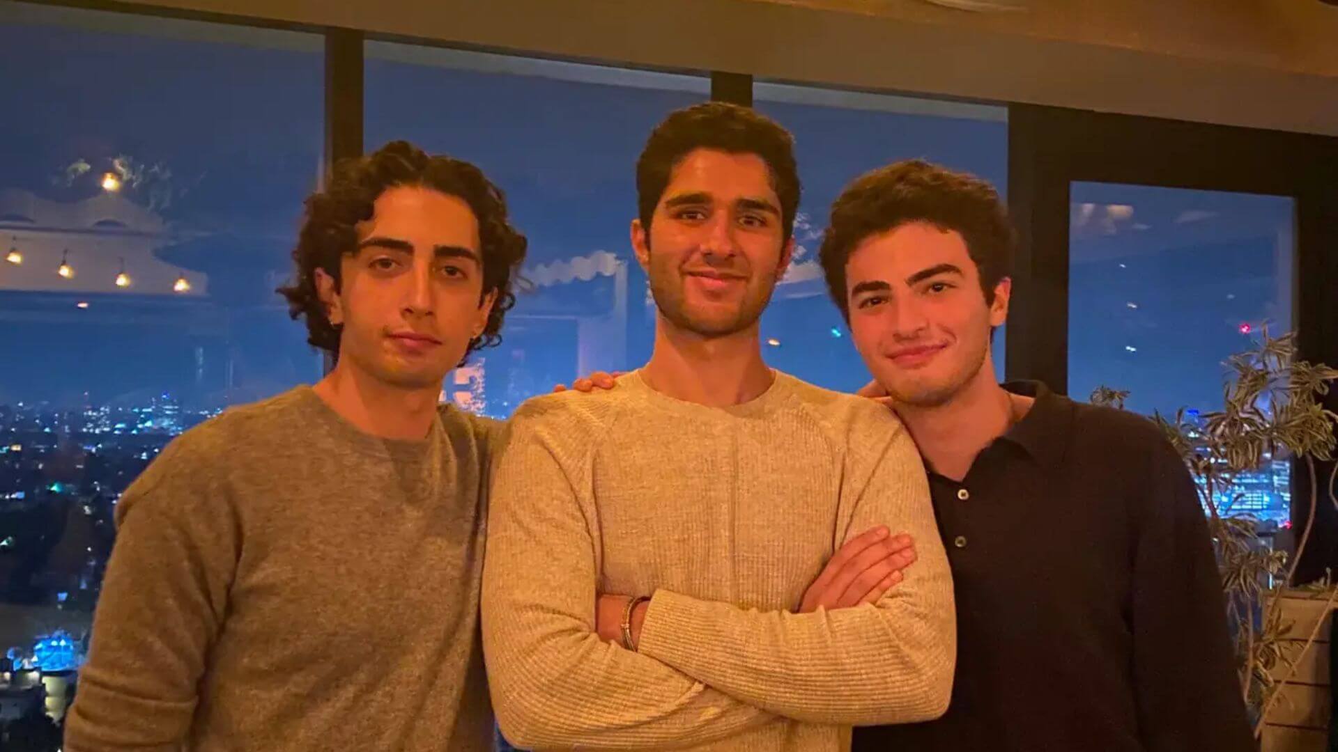 Los tres fundadores de 222 posan en un interior con vista nocturna, representantes de la app de citas centrada en encuentros presenciales.