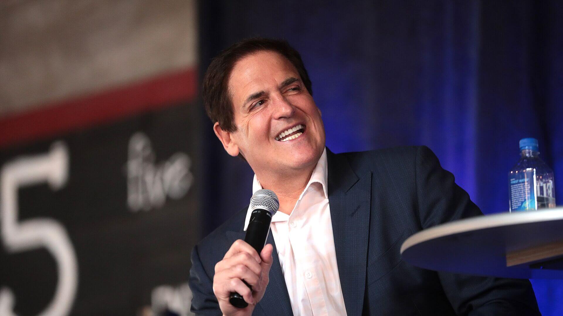 Ejecutivo sonríe con un micrófono durante una conferencia vinculada con una nota sobre Mark Cuban y la inteligencia artificial.