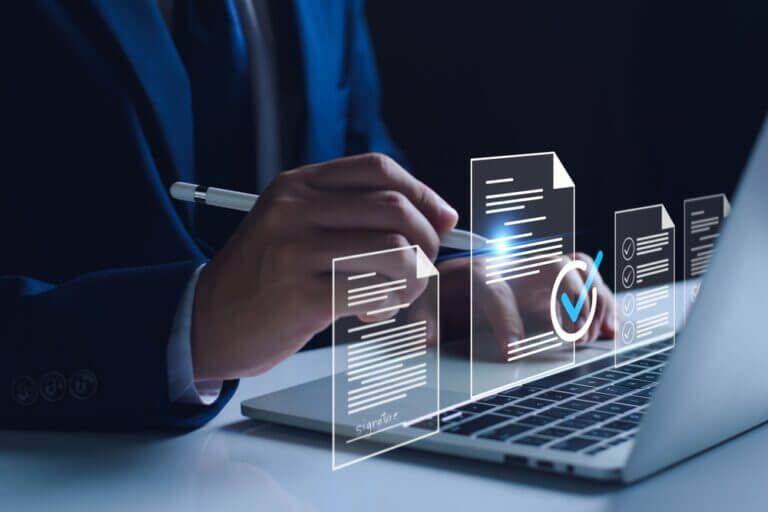Profesional usando una notebook con documentos digitales y marcas de verificación, asociado a contract analytics y trazabilidad contractual.